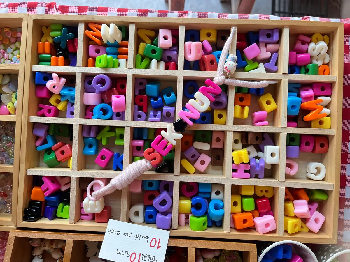 Wooden organizer with colorful alphabet beads and a bracelet.