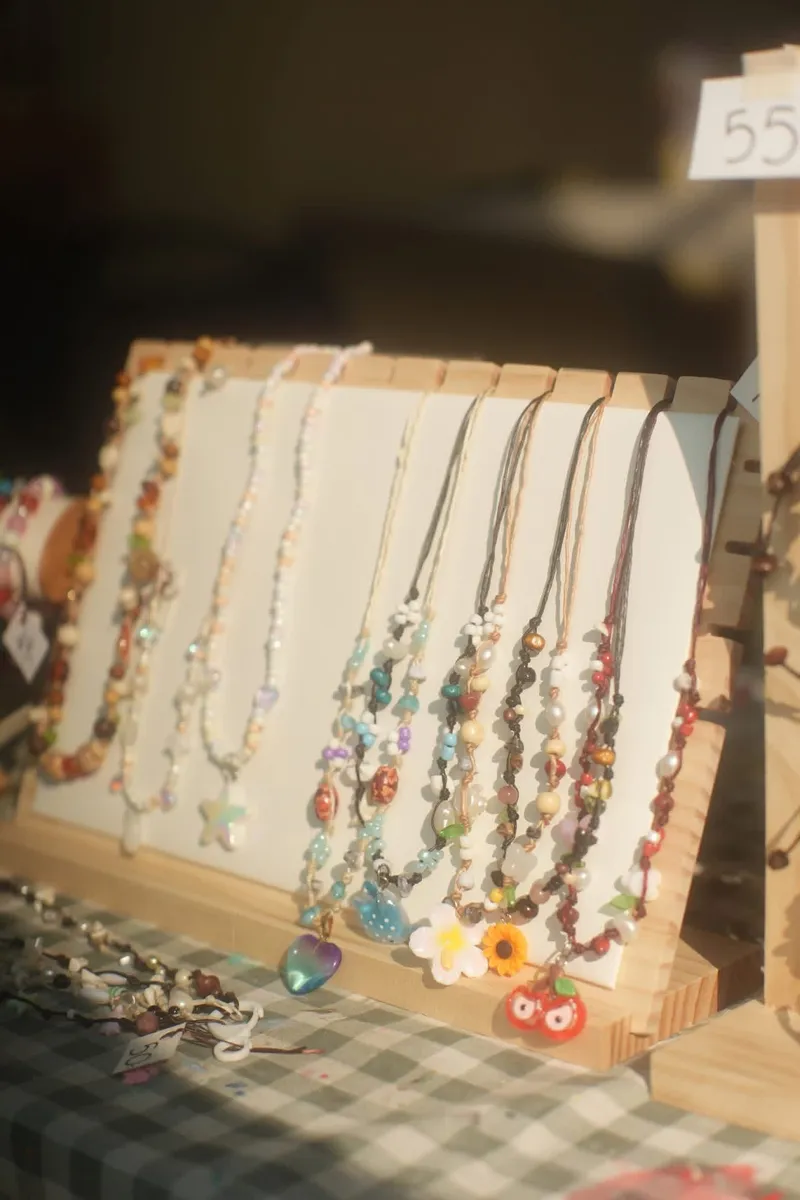Display of handmade bead necklaces on a wooden stand.