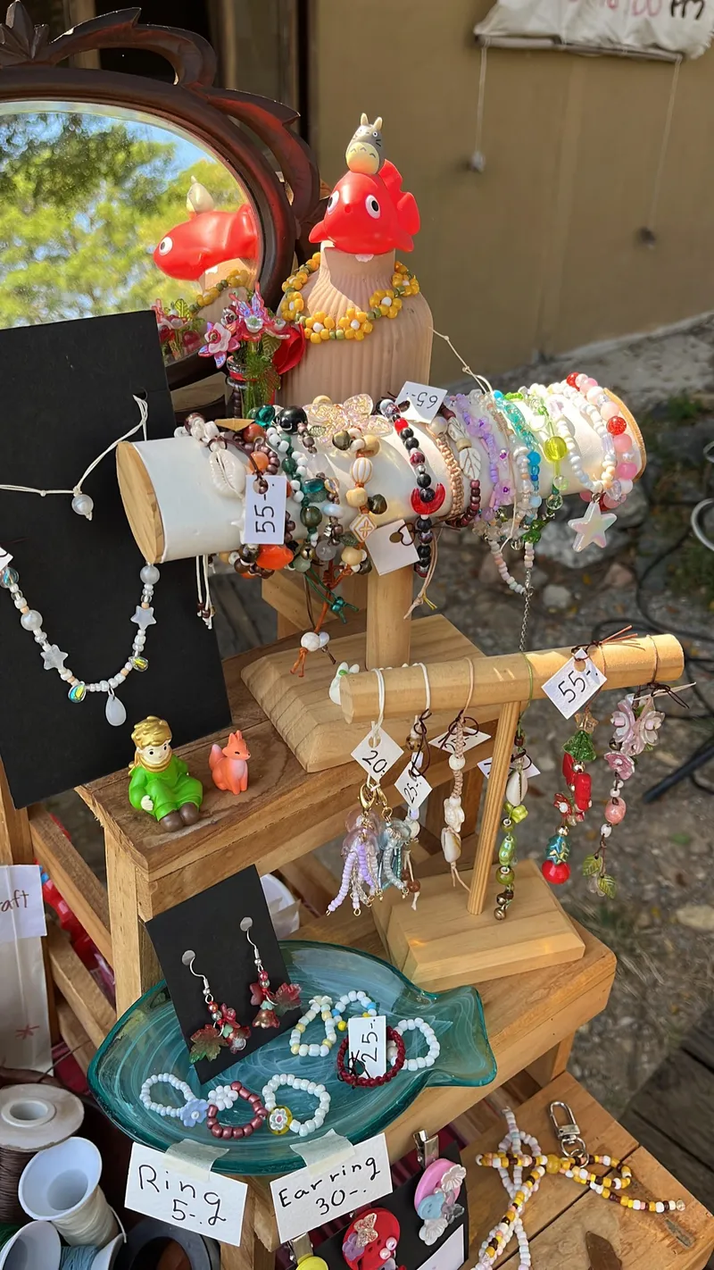 Wooden stand displaying handmade bead jewelry with price tags.