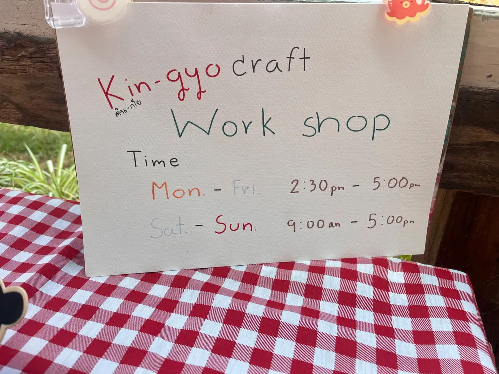 Handwritten KIN-GYO workshop hours sign on gingham tablecloth