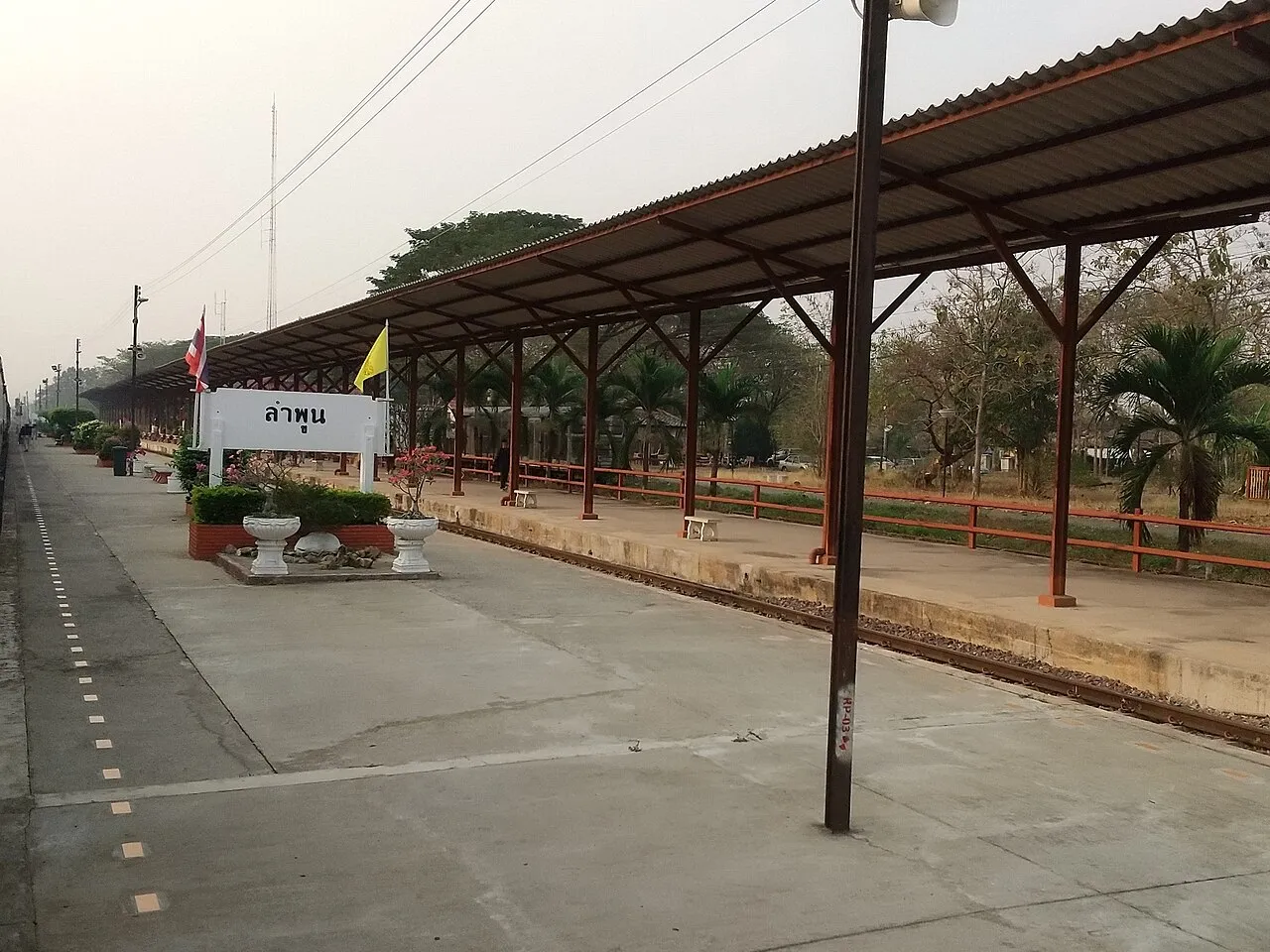 Lamphun Railway Station platform with the Thai-script station sign and red corrugated roof, the arrival point of the slow train from Chiang Mai.