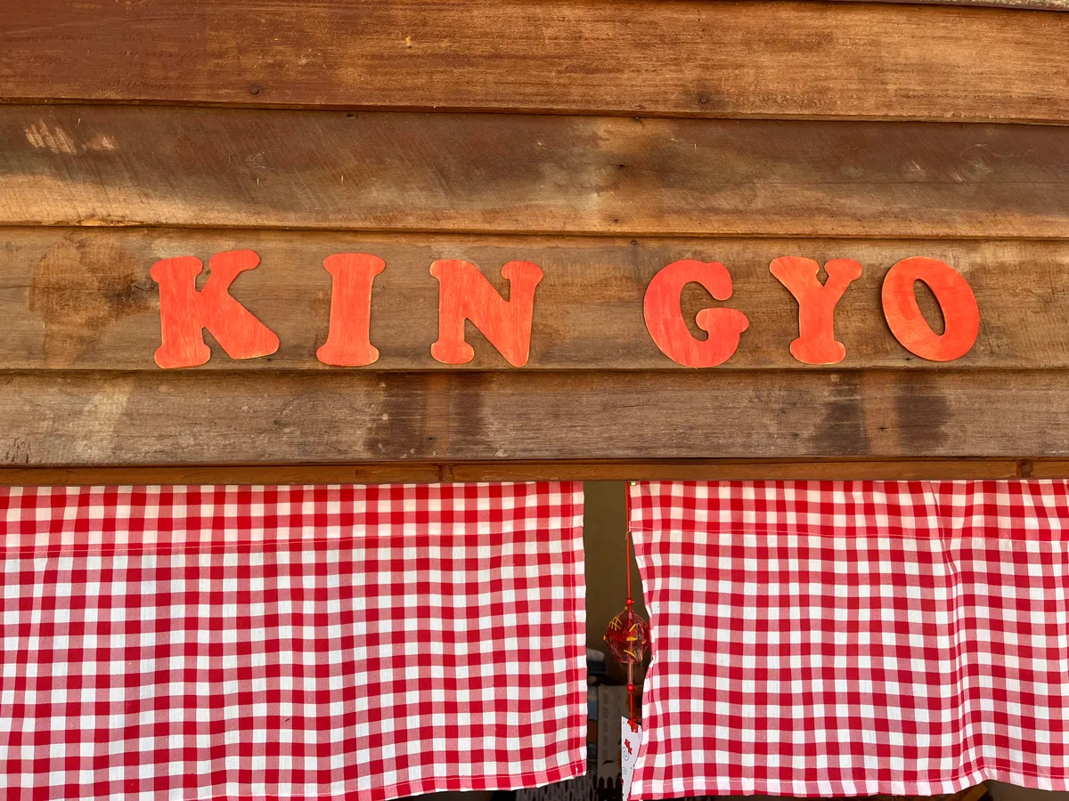 KIN GYO carved wooden sign on dark wood panels with gingham curtain