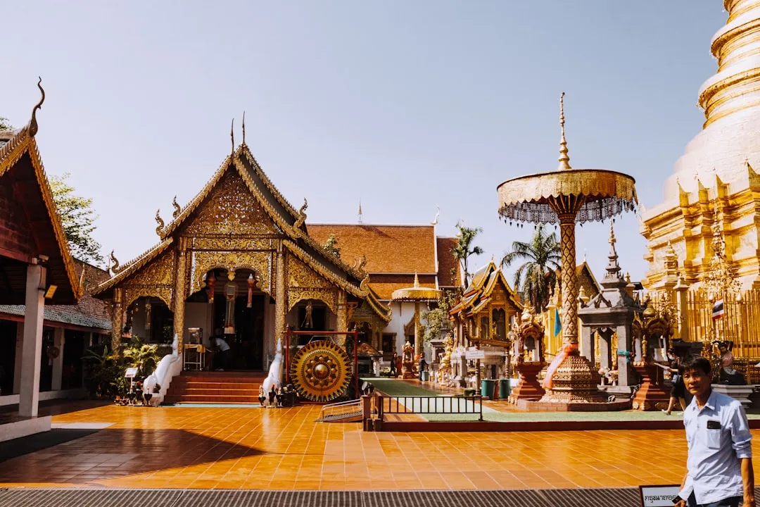 Wat Phra That Hariphunchai temple complex in Lamphun, with the gold-gabled viharn, bronze gong, ornate ceremonial parasol, and edge of the golden chedi.